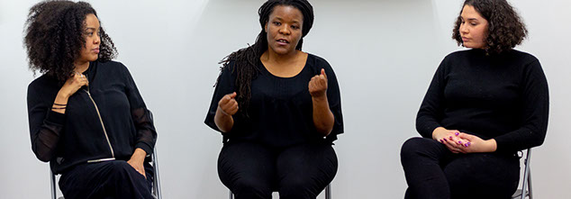 Part A: It's Speachy Three African diaspora women, all wearing black, seated in a white room.