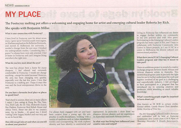 Newspaper article with text and photo of a woman smiling with make up, curly brown hair, beaded necklace and black tshirt that reads ColouredTM.