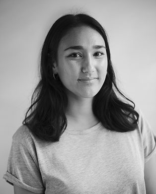Black and white image of a woman with long dark hair wearing a tshirt.